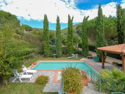 a beautiful backyard with a swimming pool , trees , and white furniture , under a blue sky with scattered clouds at Messi