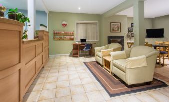 a living room with a couch , chairs , and a fireplace is shown in the image at Grand Forks Inn