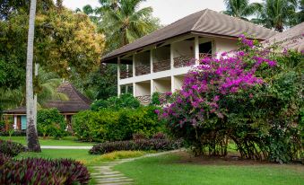 a large house surrounded by a lush green lawn , with trees and bushes in the background at Pousada Praia Dos Carneiros
