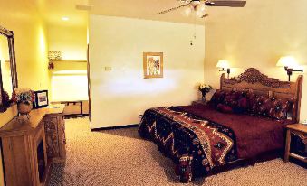 a well - decorated bedroom with a bed , nightstands , and a tv , all lit up by ceiling fans at Casa de San Pedro Bed & Breakfast