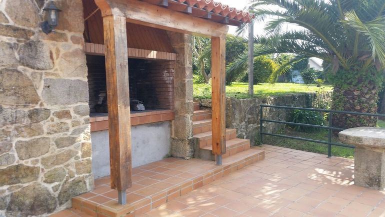 a brick patio with a barbecue grill and an outdoor seating area surrounded by trees at Casa Santos