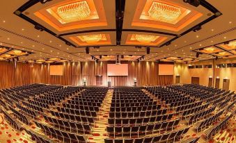 a large , well - lit auditorium with rows of black chairs and wooden paneling on the walls at Pullman Melbourne Albert Park