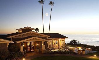 a large house with a moon shining over it , surrounded by palm trees and the ocean in the background at Montage Laguna Beach