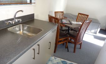 a kitchen sink with a wooden chair and table in the background , next to a dining table at Argyle on the Park