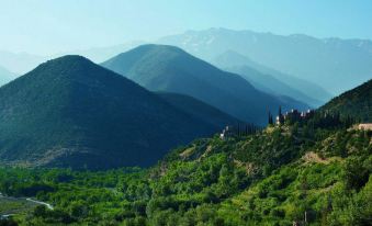 a beautiful mountain landscape with lush green trees and a small village nestled in the hills at Kasbah Tamadot