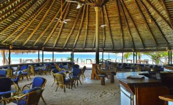 a large dining area with a thatched roof , tables and chairs , and a view of the ocean at Makunudu Island