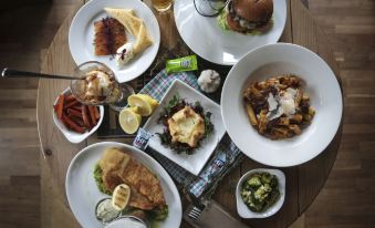 a dining table with a variety of food items , including sandwiches , burgers , and other dishes at Richmond Park Hotel