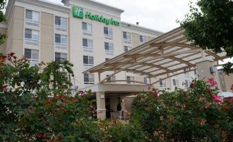 a holiday inn hotel with its sign and flowers in front of it , under a cloudy sky at Holiday Inn Portsmouth Downtown