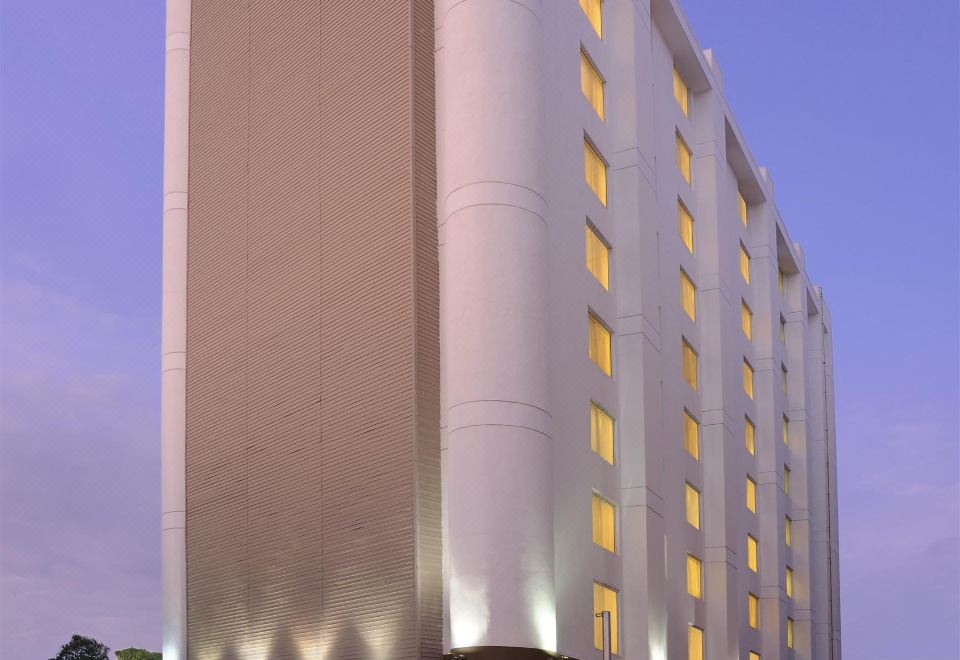 a tall hotel building with many windows and a curved structure in front of it at Four Points by Sheraton Ahmedabad