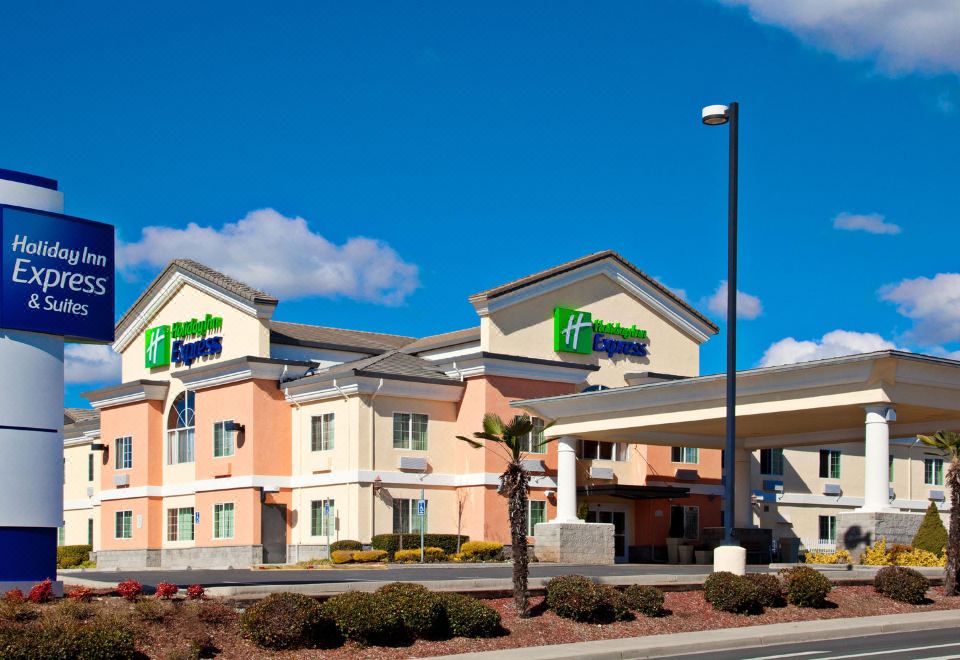 an exterior view of a holiday inn express hotel , with a large parking lot in the background at Holiday Inn Express & Suites Jackson