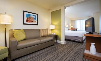 a living room with a couch , coffee table , and bed in the background , as well as a bedroom with a large window at SpringHill Suites Minneapolis Eden Prairie