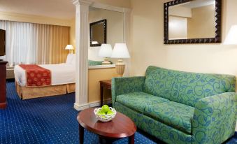 a hotel room with a bed , couch , and dining table , along with a view of the city through a window at SpringHill Suites Centreville Chantilly