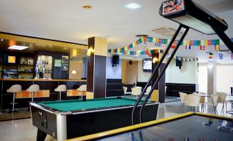 a pool table in a room with a television on the wall and chairs around it at Hotel Miami
