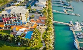 aerial view of a resort with a large pool surrounded by palm trees and a boat dock at Mantra Mackay