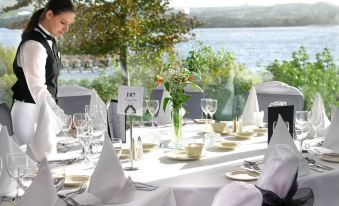 a woman in a black uniform is setting up a table at a restaurant with white tablecloths and wine glasses at Harvey's Point