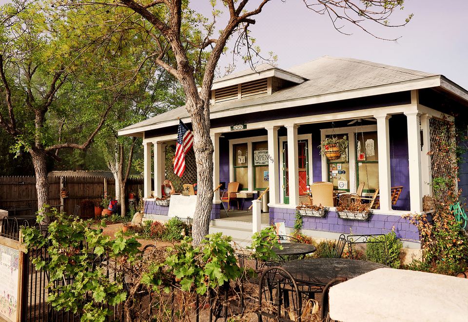 a cozy outdoor living space with a blue and white house surrounded by trees , chairs , and tables at Fiddler's Inn