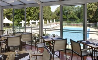 an outdoor dining area with tables and chairs , overlooking a pool area with lounge chairs at Novotel Avignon Nord