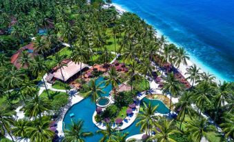 aerial view of a tropical resort with a large pool surrounded by palm trees and blue water at Holiday Resort Lombok