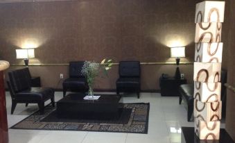 a living room with black leather chairs , a coffee table , and two lamps on either side of the couch at Hotel Mexico