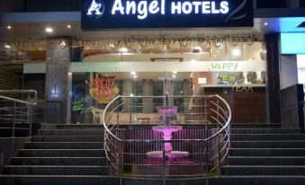 "the entrance of a hotel named "" angel hotels "" with a staircase leading up to the building and neon signs above" at Angel Hotels