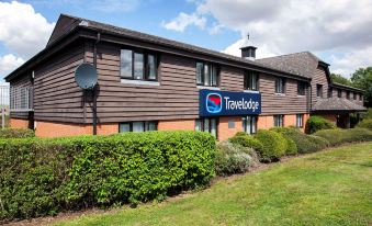 a travelodge hotel with a large sign above the entrance , surrounded by grass and trees at Travelodge Ipswich Beacon Hill