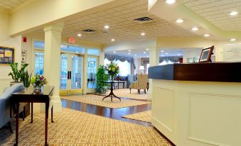 a modern hotel lobby with a reception desk , carpeted floor , and various seating arrangements , as well as plants at The Farmington Inn and Suites