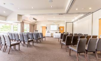 a large , empty conference room with rows of chairs and a projector screen set up for a presentation at Tides Hotel