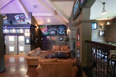 a living room with brown leather couches , a coffee table , and a television mounted on the wall at Village Hotel Liverpool