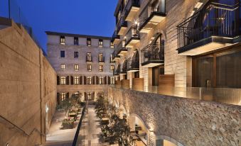 a modern , stone building with balconies and outdoor seating areas , illuminated by lights at night at The Setai Tel Aviv, a Member of the Leading Hotels of the World