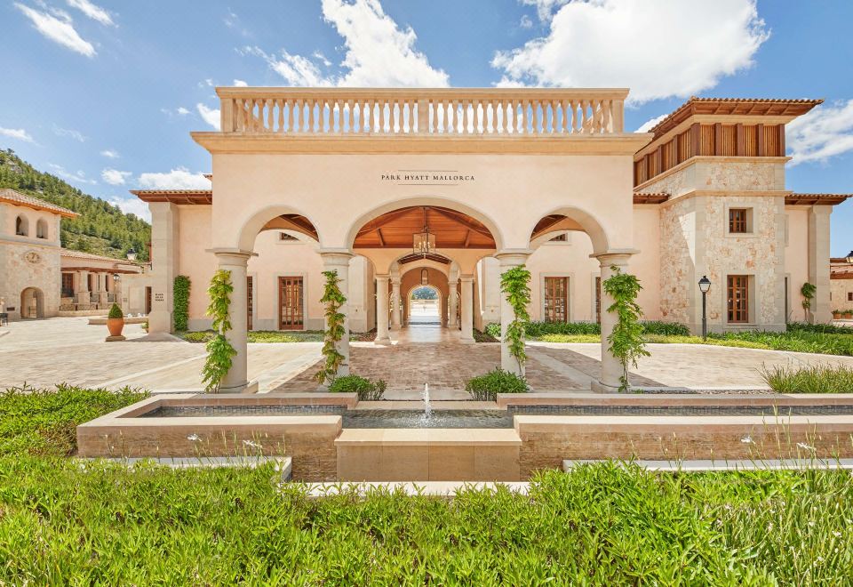 a grand entrance to the monterey plaza hotel , with intricate stone arches and balconies , leading to a large fountain in the foreground at Cap Vermell Grand Hotel