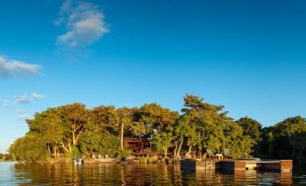 a serene lake with boats floating on the water , surrounded by lush green trees and a small wooden house at Jicaro Island Lodge Member of the Cayuga Collection