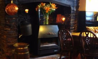 a cozy living room with a fireplace , a dining table , chairs , and a television mounted on the wall at The Who'd Have Thought It Inn