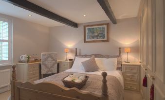 a cozy bedroom with a wooden bed , white bedding , and two nightstands on either side of the bed at Marsh House Farm