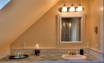 a bathroom with a white sink , mirror , and three lights above it , along with a hand dryer on the counter at Gibson House