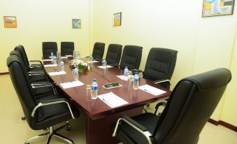 a conference room with a large wooden table , black chairs , and white papers on the table at Raphael's Hotel