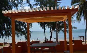 a wooden structure with a table and chairs , overlooking the ocean and trees , under a clear blue sky at World Cat Hotel Beach & Resort