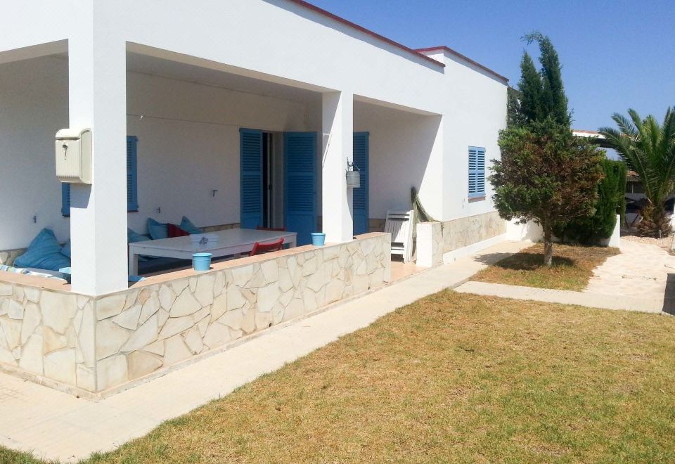 a house with a white exterior and blue shutters is surrounded by a grassy yard at Casa Amigos