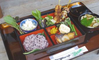 a wooden tray filled with a variety of japanese dishes , including rice , fish , and vegetables at Saraya