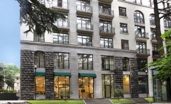 a modern building with multiple floors , balconies , and large windows , surrounded by trees and greenery at Citrus Hotel