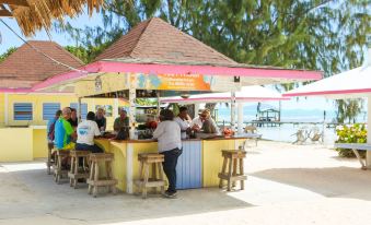 a beach bar with people standing around it , enjoying drinks and the view of the ocean at Anegada Reef Hotel