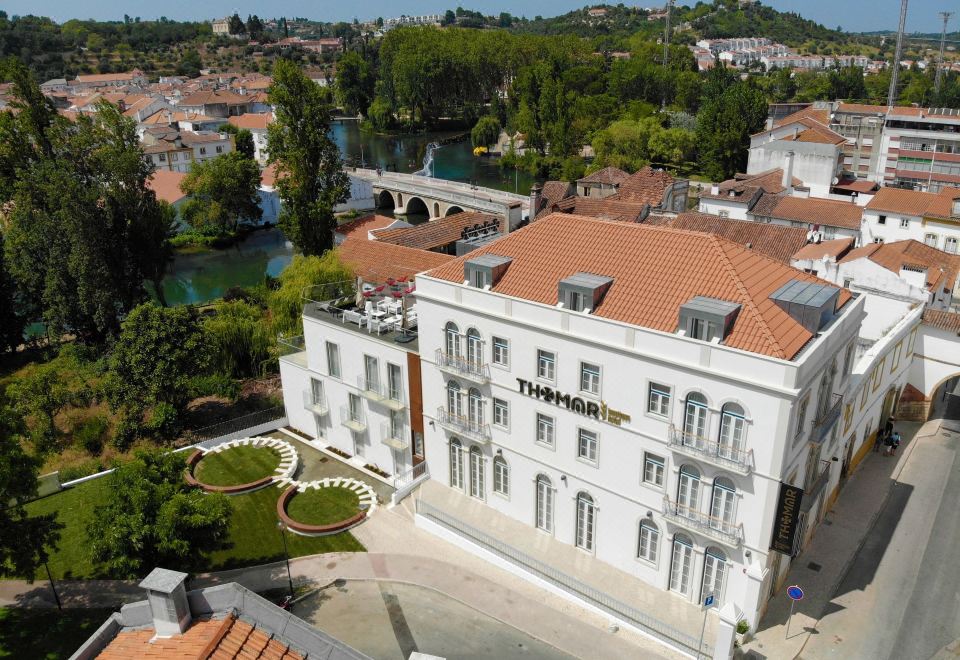 an aerial view of a city with a large white building , surrounded by trees and water at Thomar Boutique Hotel