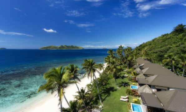a tropical beach resort with white sand , palm trees , and blue ocean , under a clear sky at Matamanoa Island Resort