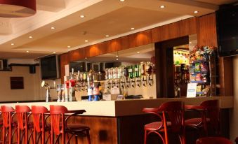 a modern bar with wooden paneling , multiple stools , and various bottles of liquor on display at Abbotsford Hotel