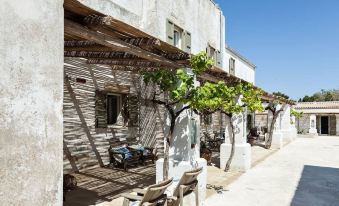 a row of chairs and tables under a pergola on the sidewalk , with trees and buildings in the background at Borgo Sentinella