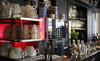 a modern coffee shop with an espresso machine , surrounded by various cups and mugs on display at Schlosshotel
