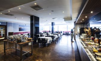 a large dining room with wooden floors , tables , and chairs arranged for a group of people at Best Western Plus Airport Hotel Copenhagen