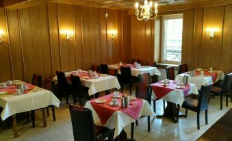 a large dining room with wooden walls , tables set for a meal , and chandeliers hanging from the ceiling at Hotel Brunnenhof