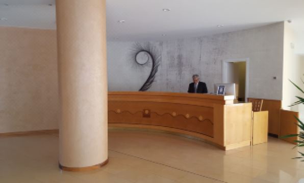 a man standing behind a reception desk in a modern office building , talking on the phone at Grand Hotel Moon Valley