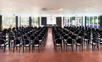 a large conference room filled with rows of black chairs and a podium in the center at Hotel Da Vinci