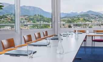 a long white table with a clear glass vase on it is set up in front of a window overlooking a mountainous landscape at Suitenhotel Parco Paradiso